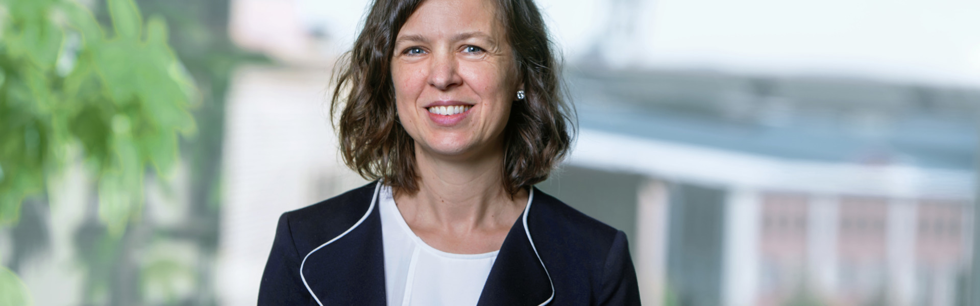 Linda Sörensson, utsedd till ny CFO på Stena Fastigheter. Linda bär en mörkblå kavaj, och. vit tröja. Hon har brunt, halvlångt hår och ler mot kameran