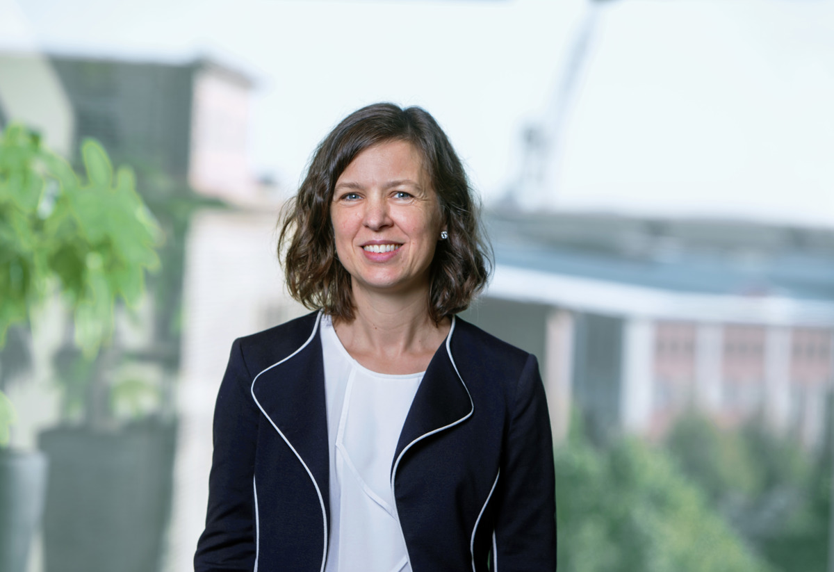 Linda Sörensson, utsedd till ny CFO på Stena Fastigheter. Linda bär en mörkblå kavaj, och. vit tröja. Hon har brunt, halvlångt hår och ler mot kameran