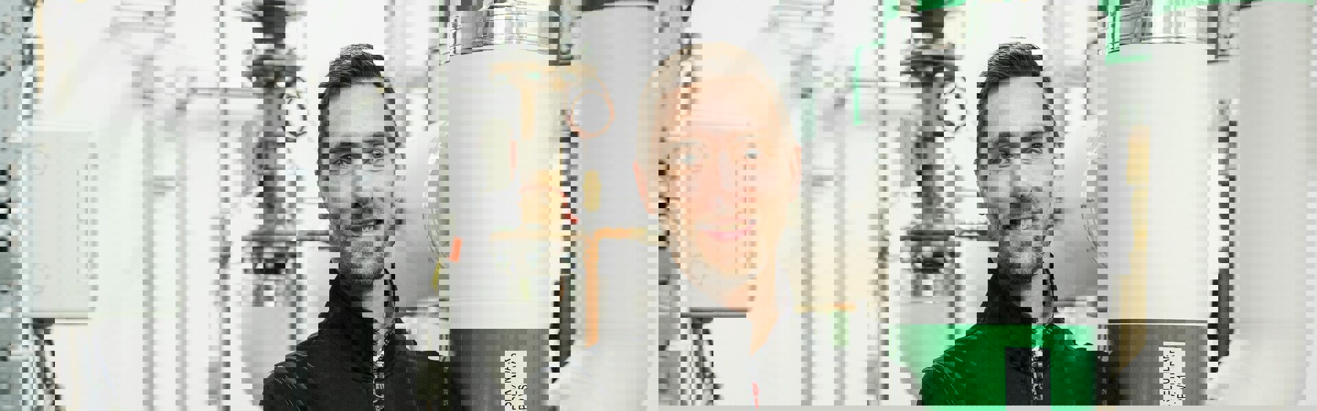 En man som står med armarna i kors och tittar in i kameran. Han står i ett teknikrum som är en del av hans arbetsvardag och miljö.