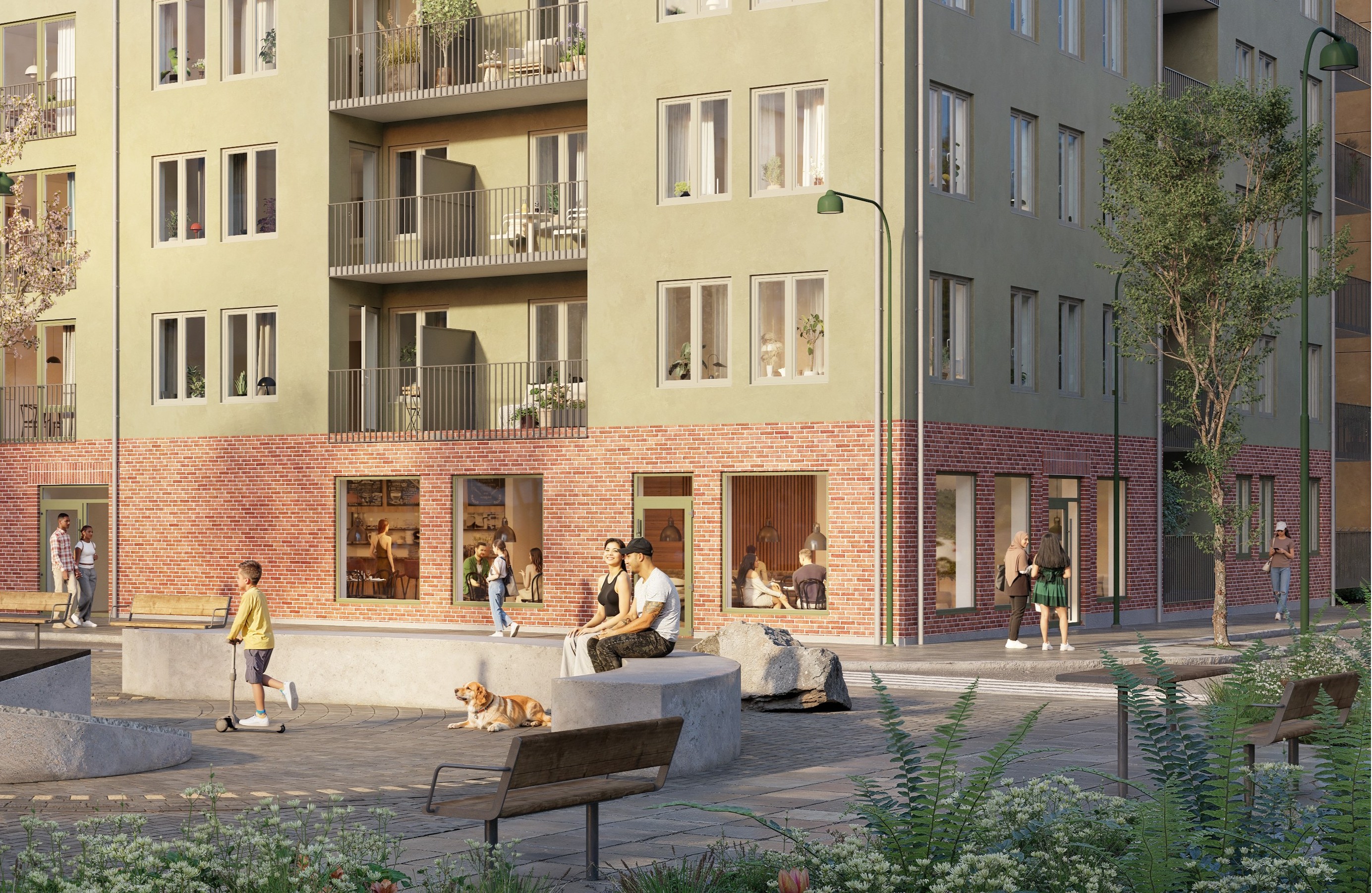 En solig innerg&aring;rd framf&ouml;r ett flerbostadshus med gr&ouml;n fasad och r&ouml;d tegelsockel, d&auml;r m&auml;nniskor i olika &aring;ldrar sitter p&aring; b&auml;nkar, pratar, leker och promenerar bland tr&auml;d, planteringar och l&aring;ga betongmurar.