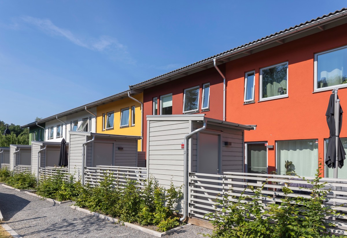 Foto på innergården till Sommartriangeln där vardera hus har en baksida med gräsmatta och altan.