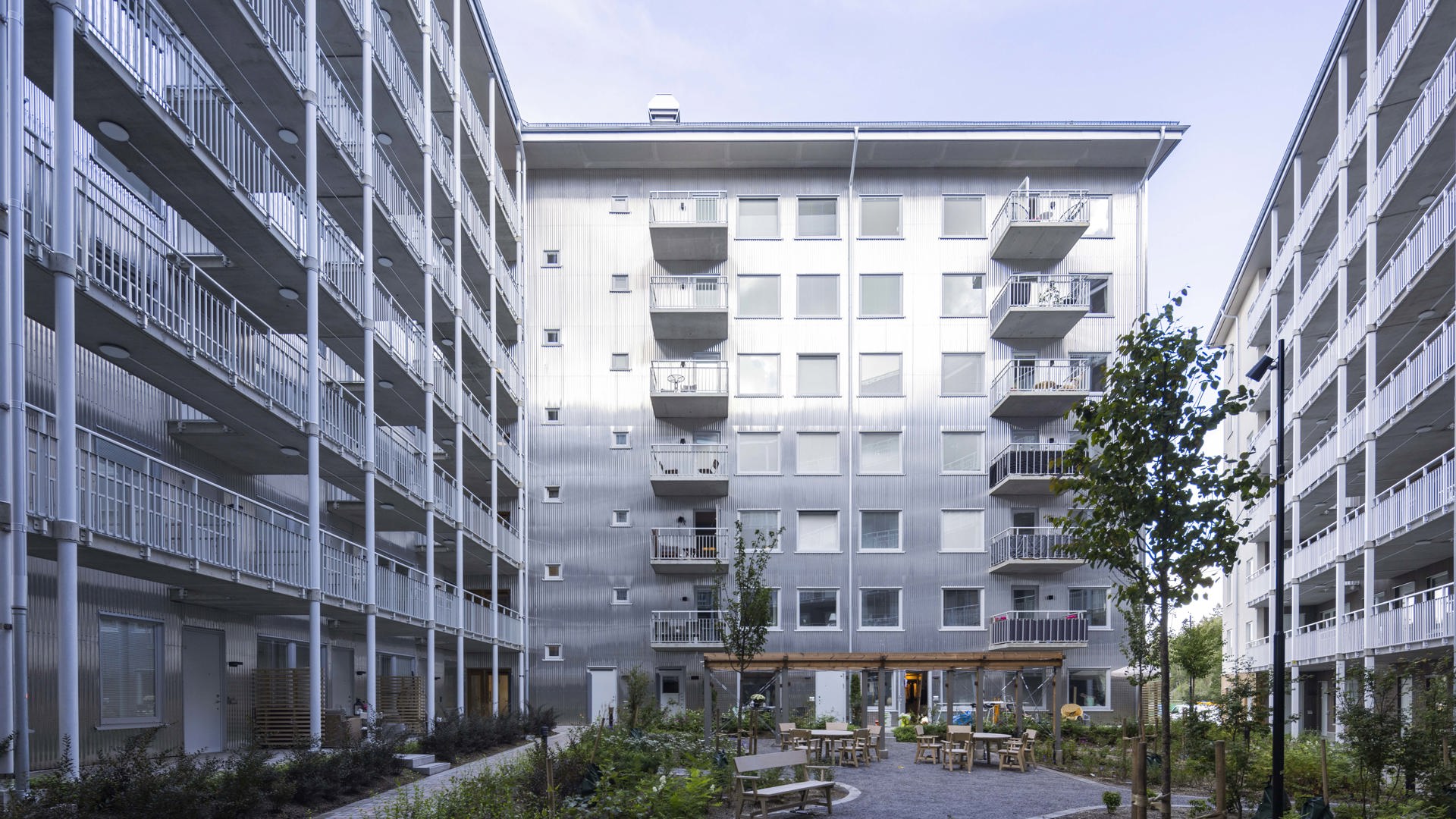 Grönskande innergård omgiven av buskar och träd.
