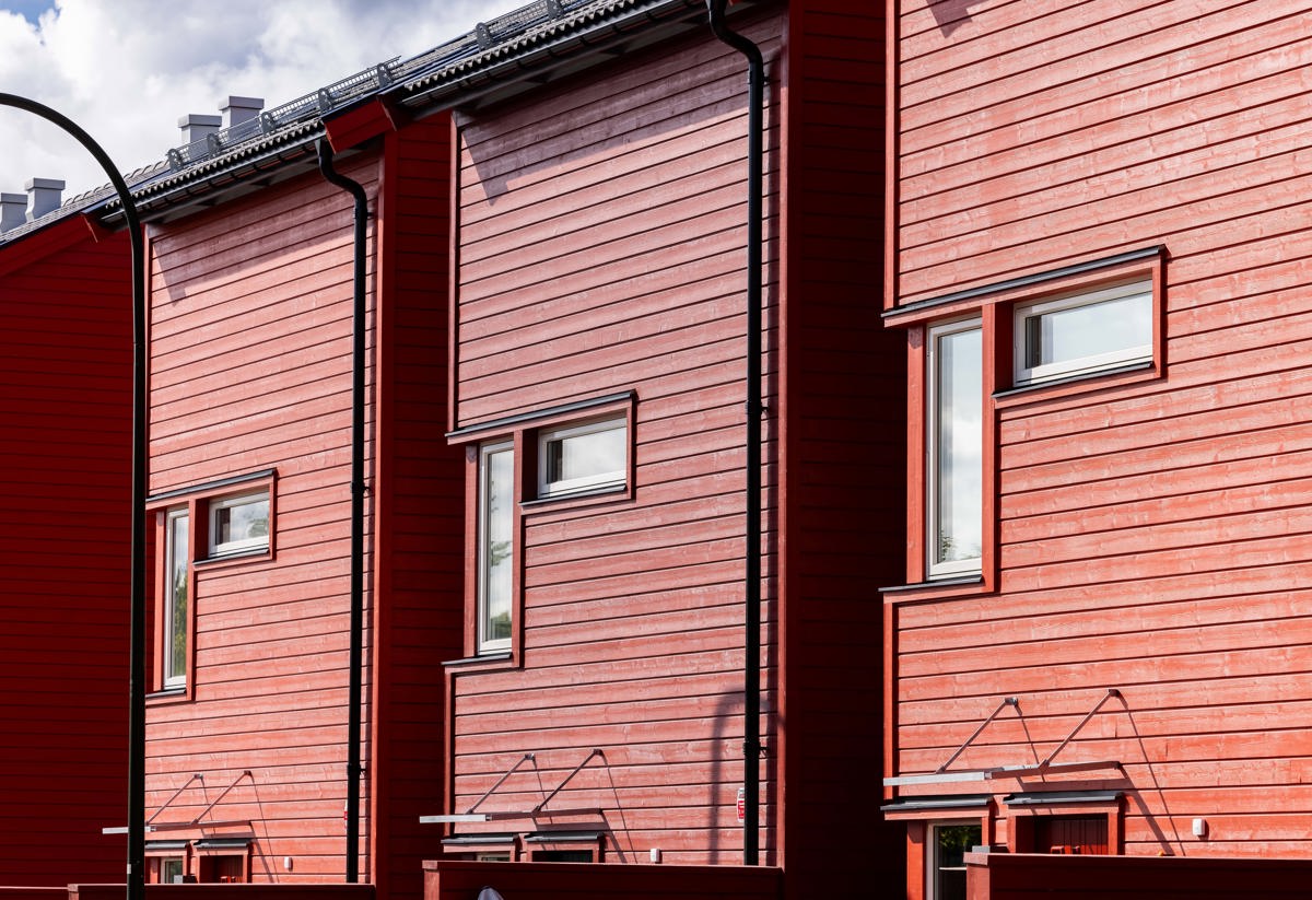 Närbild på fönster och fasaden som är röd träpanel