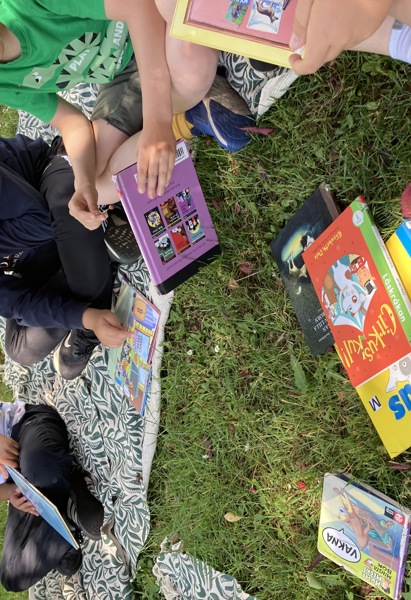 Barn sitter i en ring med böcker i mitten