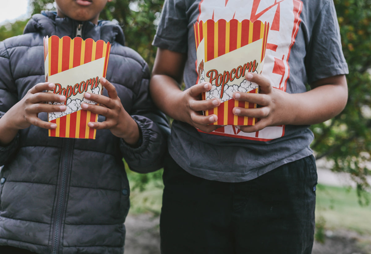 Två mindre barn som håller i varsin popcorn bägare fylld med popcorn på en av stena fastigheters gårdsfester som är en del av relationsförvaltningen och arbetet med trygga och trivsamma kvarter