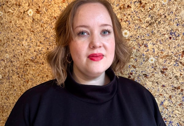 Bild på en kvinna med axellångt brunblont hår, hon bär en blåsvart polotröja. Hon titar in i kameran. Porträttbild på Sarah Pettersson, chef social hållbarhet Stena Fastigheter Stockholm