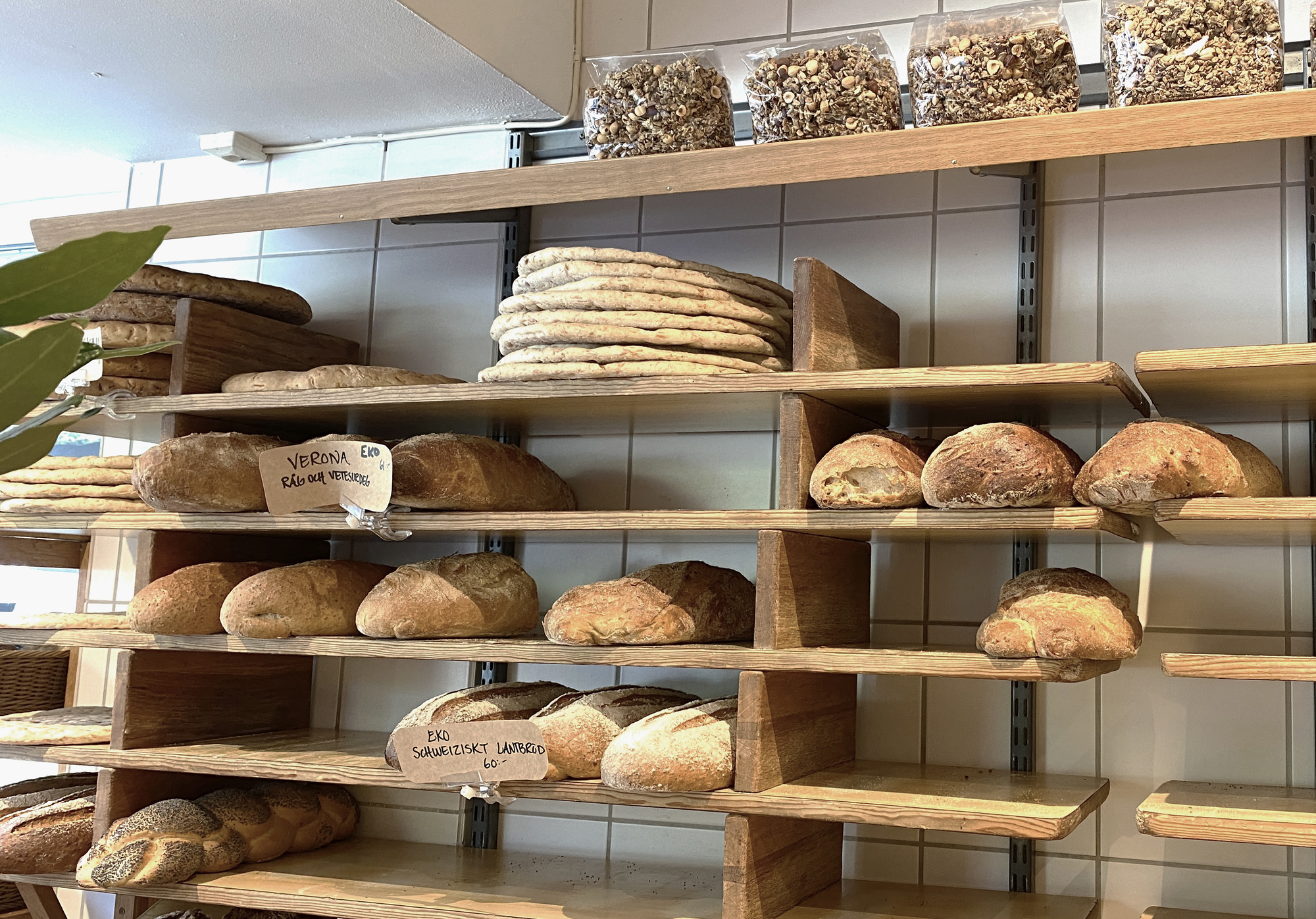 Trähyllor med bröd och bullar i olika stilar på hyllorna