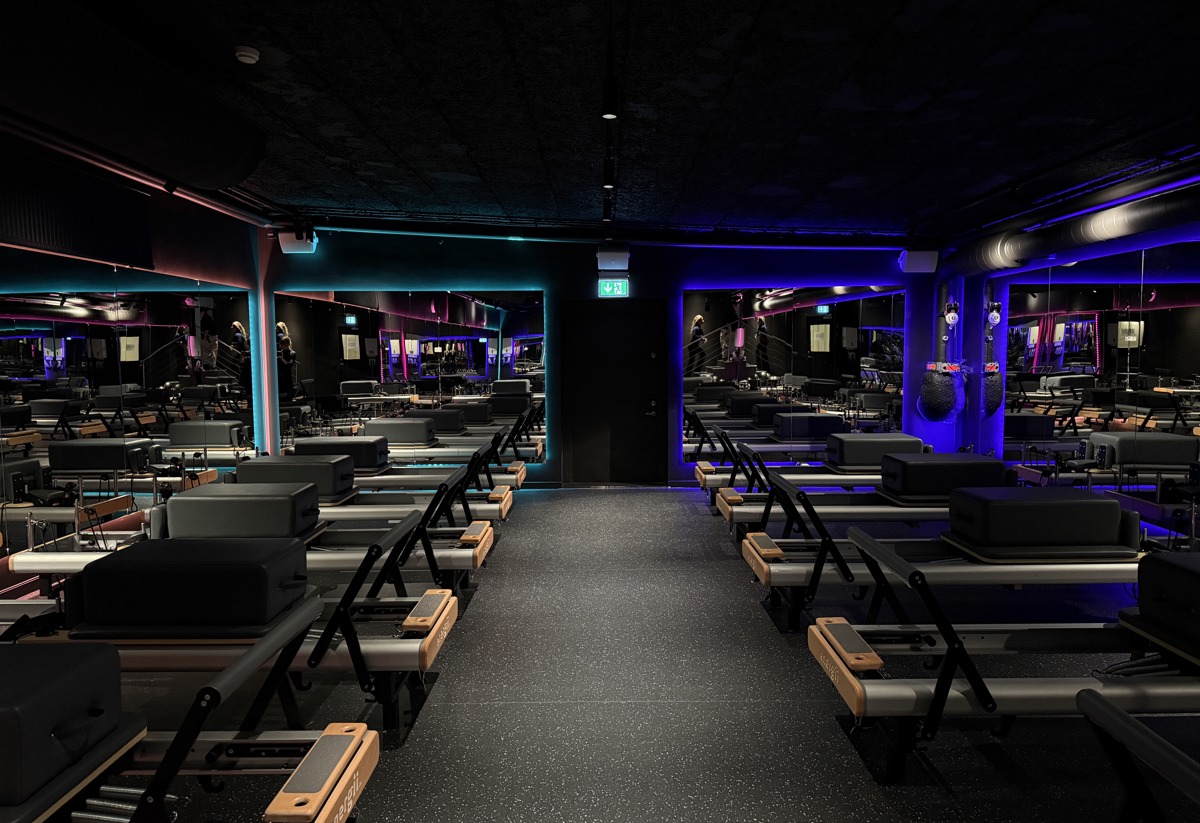 Pilatesstudion och alla maskiner. Mörkt rum med färgglad belysning. 