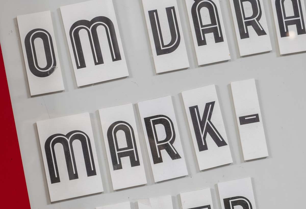 Skylt med texten 'Läs mer om våra marknader' skriven med svarta bokstäver på vita kort, uppsatta på en ljus bakgrund.