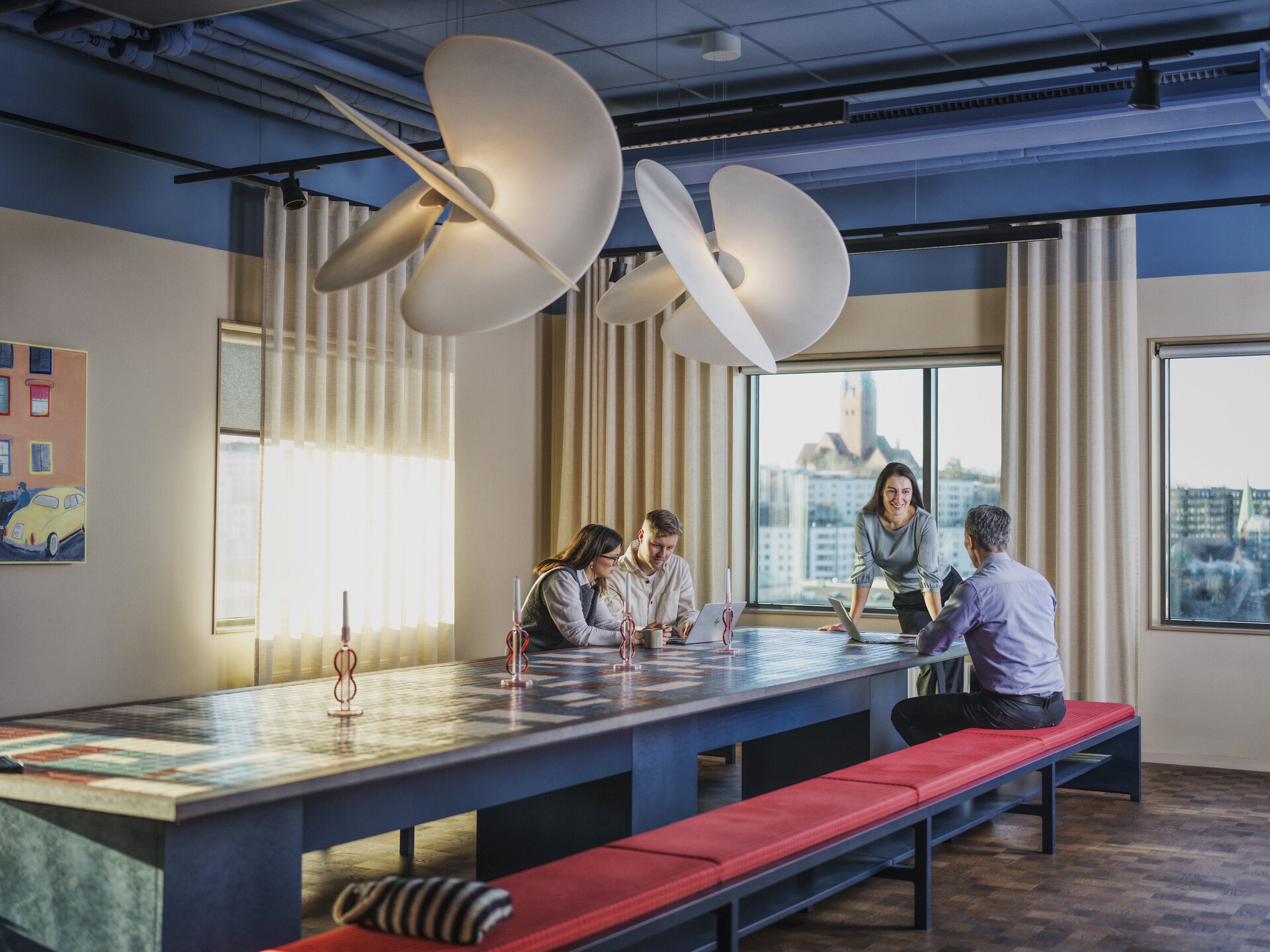 Fyra personer sitter längst bort i ett modernt inrett mötesrum med stora fönster