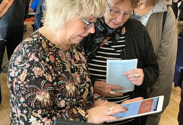 Sari Isberg hjälper Lena Hafström att registrera sig för Stena Fastigheters nyhetsbrev om nyproduktion på www.stenafastigheter.se/nyproduktion