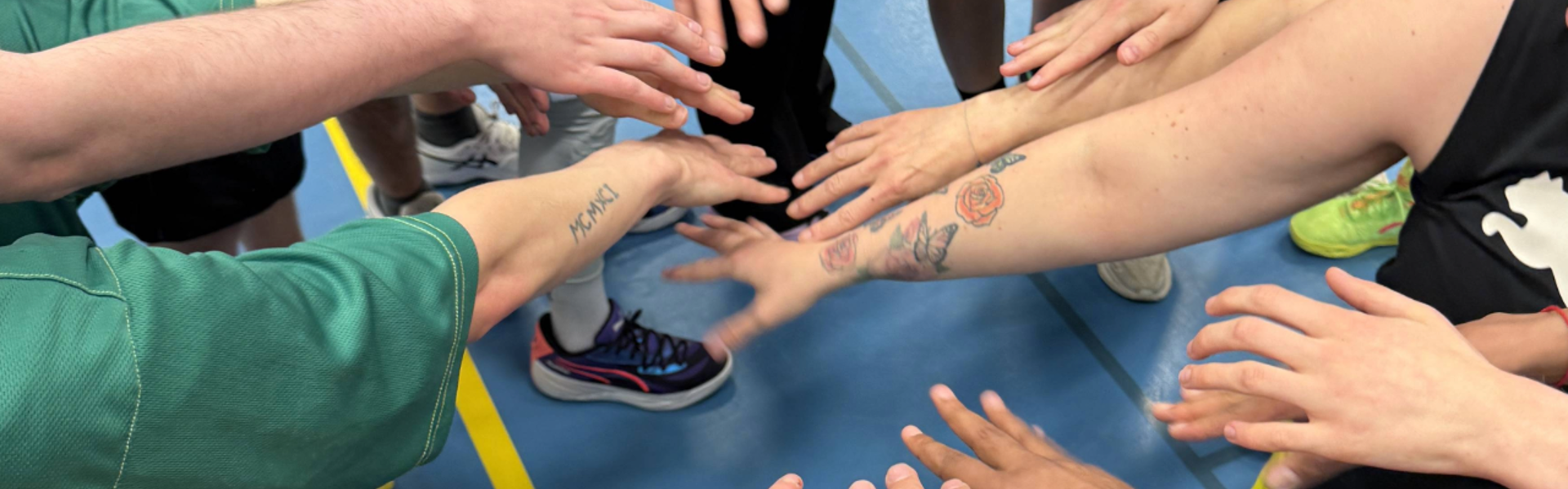 Bild på flera händer i Alvik Basket som håller in handen i mitten för gemenskap och laganda