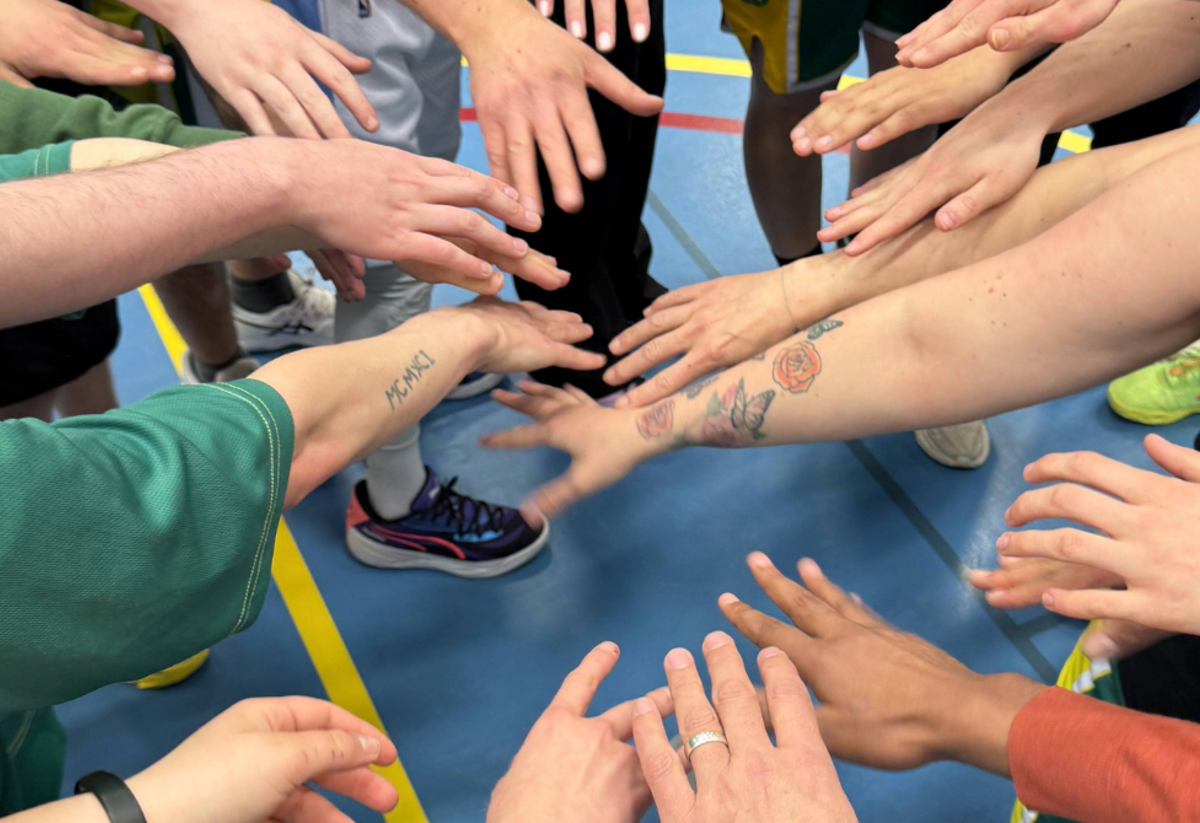 Bild på flera händer i Alvik Basket som håller in handen i mitten för gemenskap och laganda