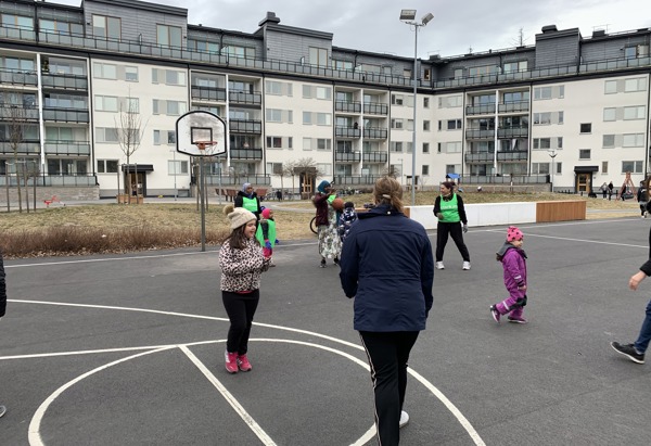 Barn i olika åldrar leker på en basketplan utomhus.