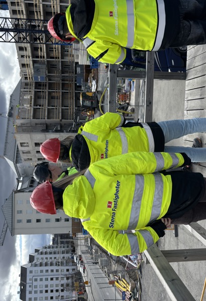 Personer som står med ryggen mot kameran och fotar ett bygge