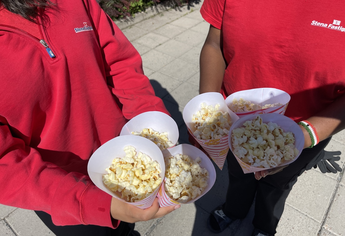 Två personer i röda tröjor som håller strutar fyllda med popcorn.