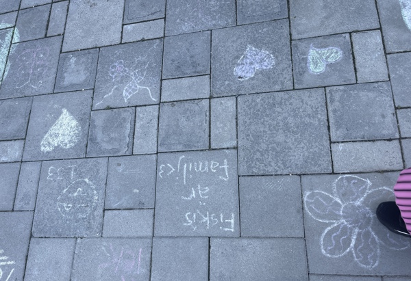 markplattor som är målade med kritor. Texten "Fiskis är familj", målade hjärtan och blommor.