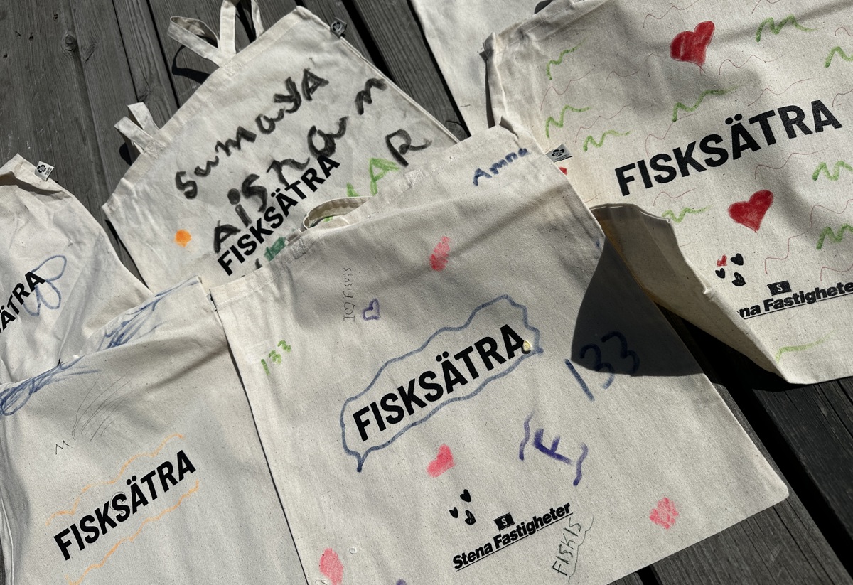 Tygkassar tryckta med Fisksätra och Stena Fastigheters logga. Färglagda och designade på olika sätt.