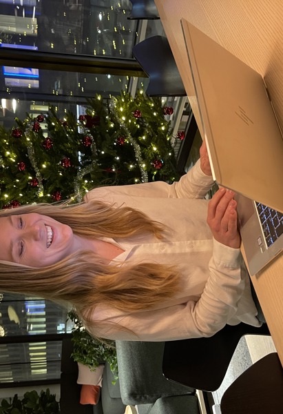 kvinna som sitter framför laptop på kontor som är julpyntat.