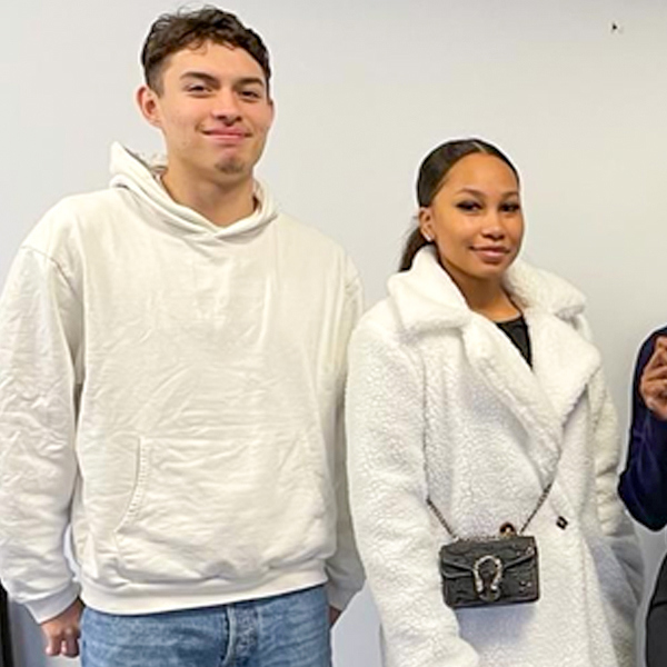 Bild på en man och kvinna mot en vit väg. Båda klädda i vitt.