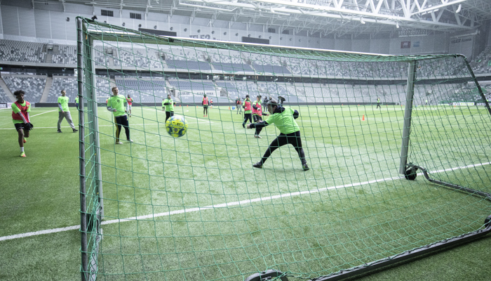 Baksidan av ett fotbollsmål där man ser hur ett gäng spelar fotboll och bollen är på väg in i mål. 