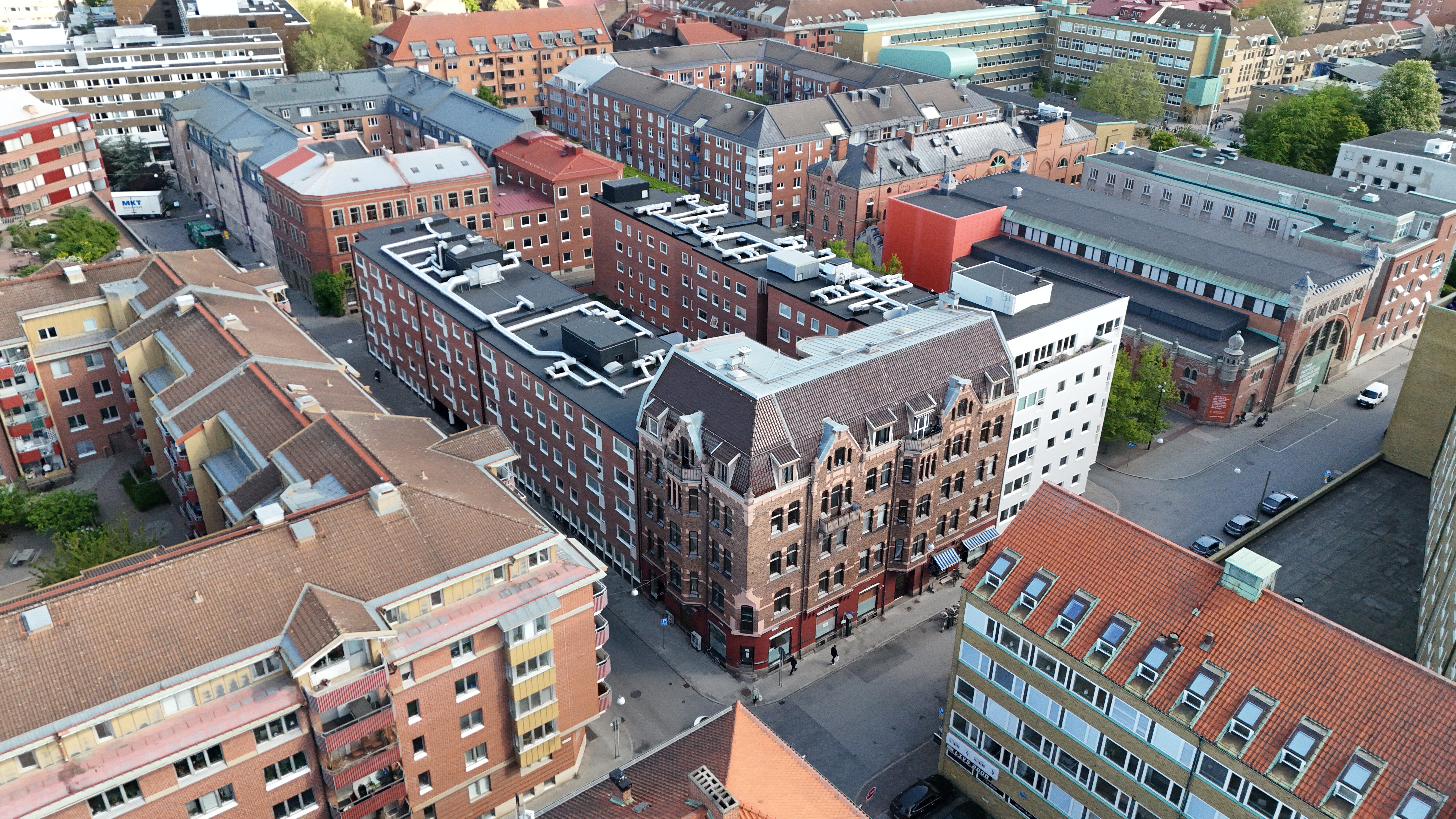 Flygbild över ett stadskvarter med flera flerbostadshus och kontorsbyggnader, där en röd markering visar en byggnad i mitten.