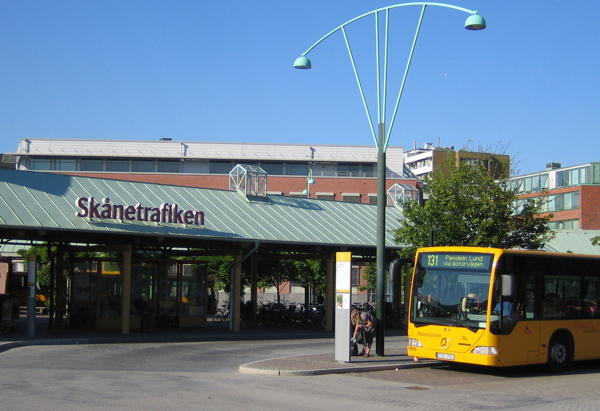 Bussterminalen vid Skånetrafiken, med en gul stadsbuss redo för avgång. Den gröna byggnaden i bakgrunden fungerar som vänthall, tydligt märkt med Skånetrafikens logga.