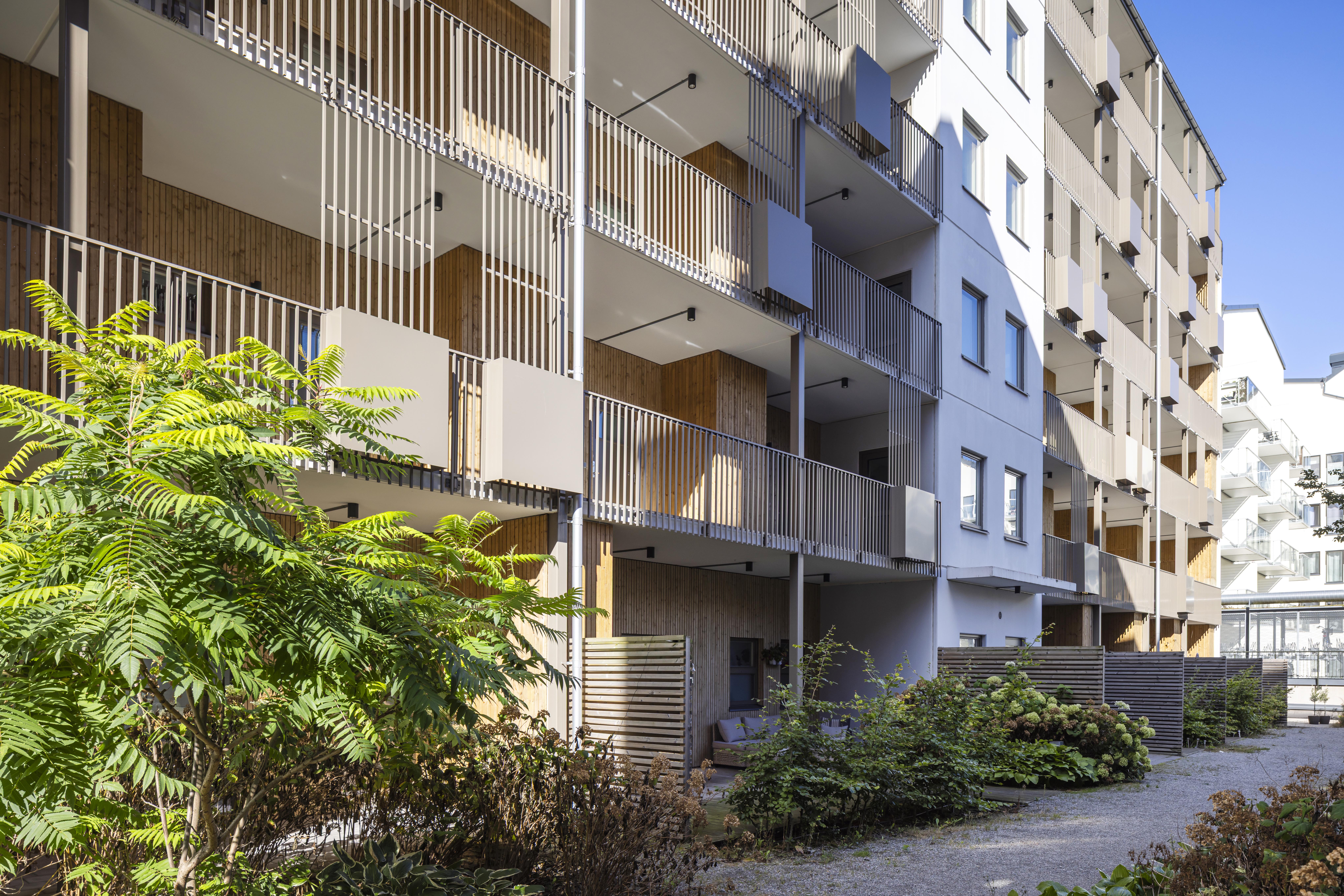 Flerbostadshus i Barkarby med balkonger och grönska på innergården.