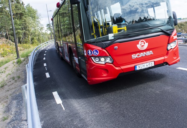 En röd buss som åker på en väg.