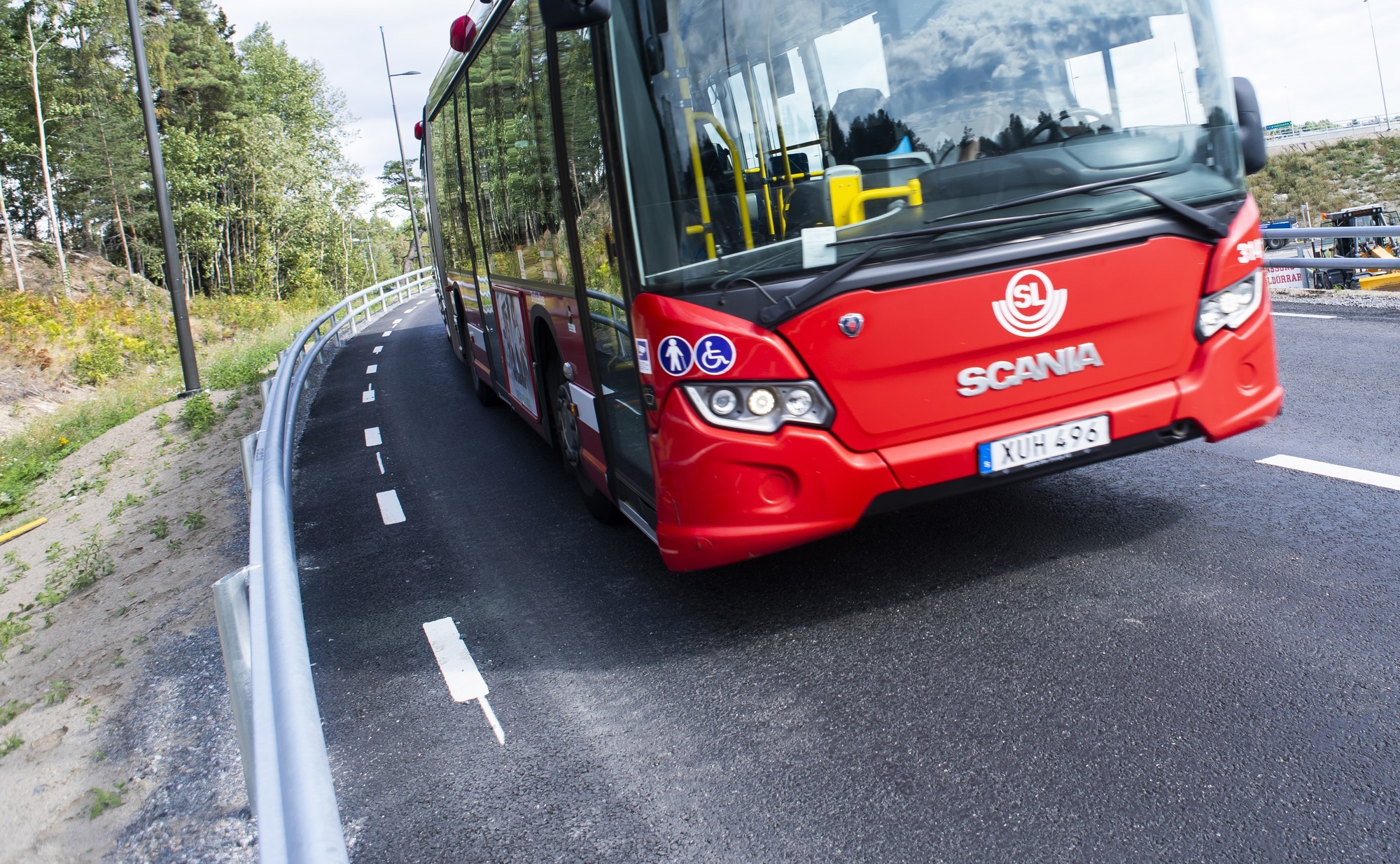 En röd buss som åker på en väg.
