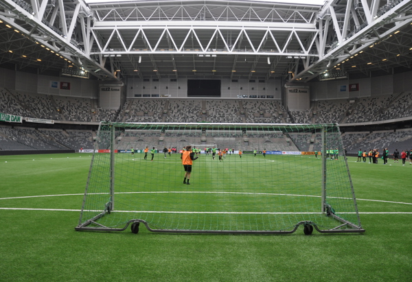 En fotbollsarena fotad från kortsidan med barn som spelar fotboll.