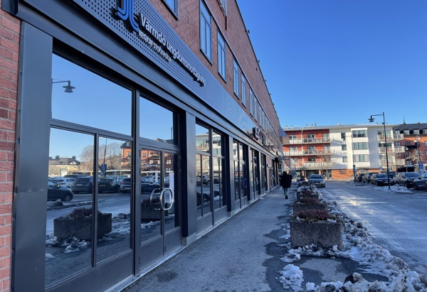 Ett hus där fasaden är i tegel med stora fönster. 