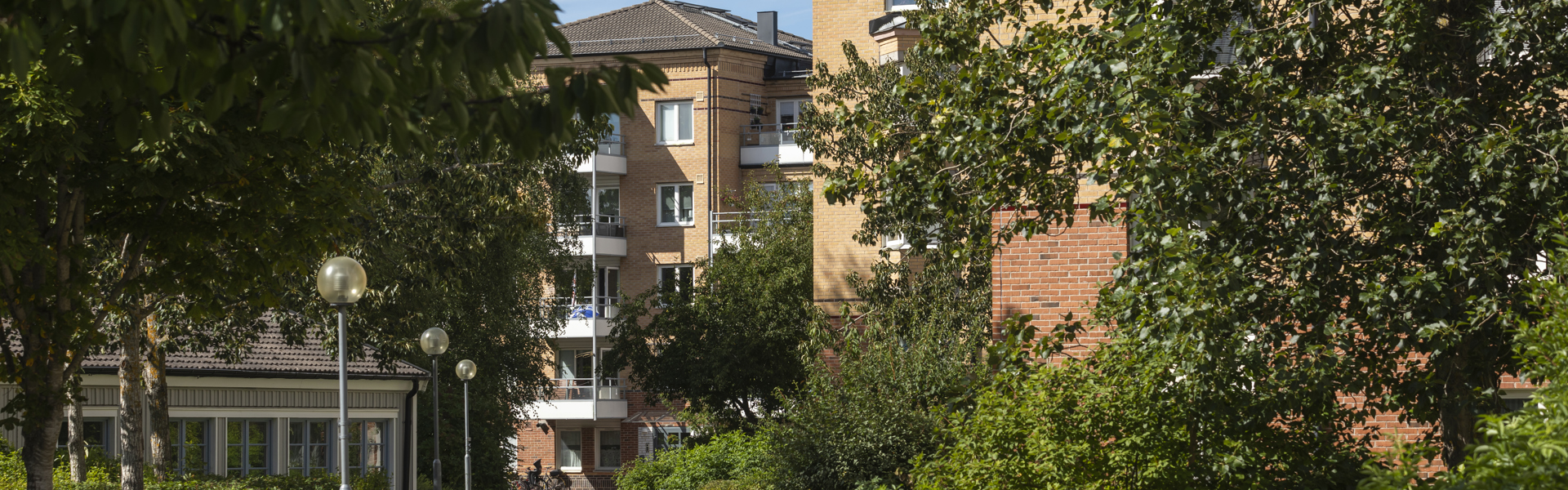 Bostadsområde med flerfamiljshus och gröna träd.