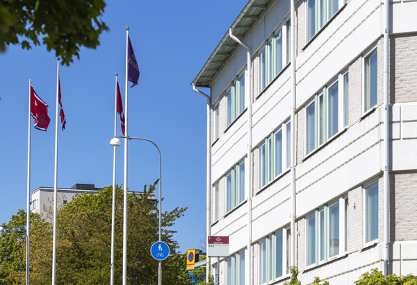 Ett vitt hus med mycket fönster och träd i förgrunden.