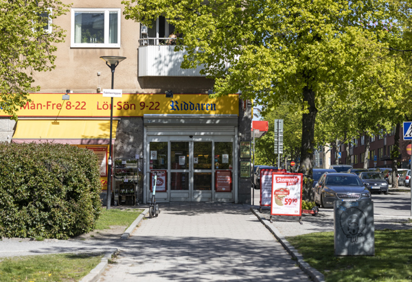 Entrén till en matbutik med grönskande träd intill entrén.