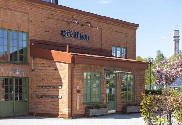 Café i ett tegelhus med gröna fönsterramar.