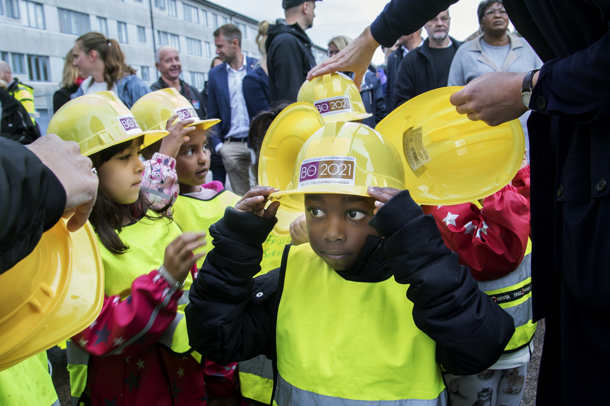 Bild på barn i bygghjälmar i samband med spadtag för BoStad2021