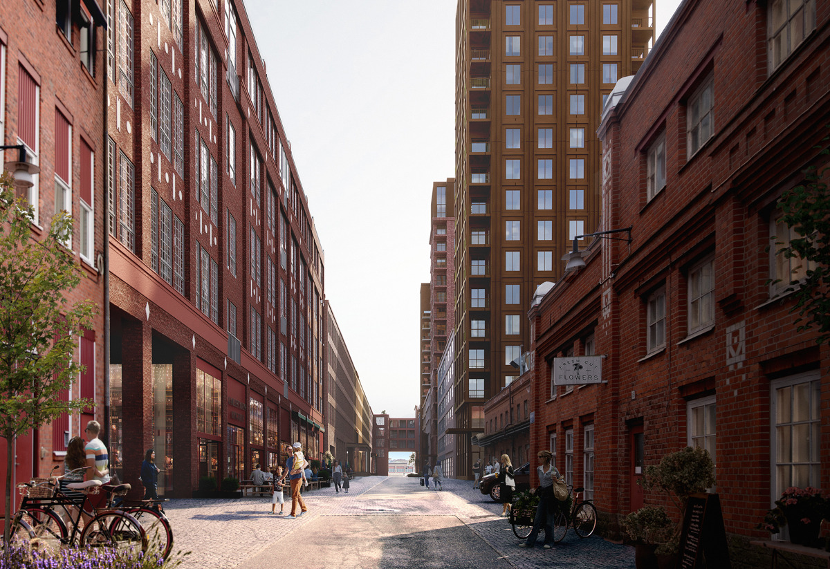 “Solbelyst stadsgata med rödtegelbyggnader på båda sidor, människor som promenerar och sitter vid uteserveringar, samt ett högt modernt bostadshus i bakgrunden.”