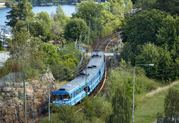 Foto på Saltsjöbanan med skog längs spåret, fotad ur ett fågelperspektiv.