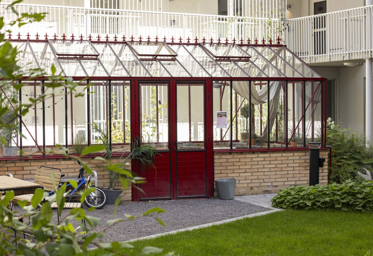 Orangeri på innergården omgivet av grönska och bostadshus