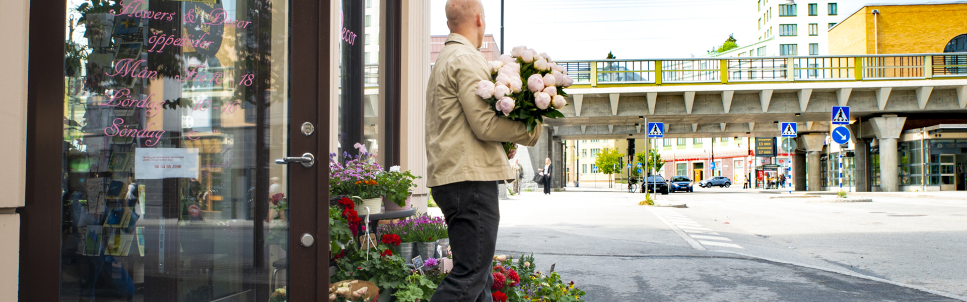 Man med blommor i handen som kommer ut från butik i Vega