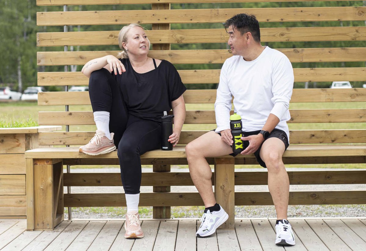 Två personer sitter på en bänk vid Rudan och pustar ut