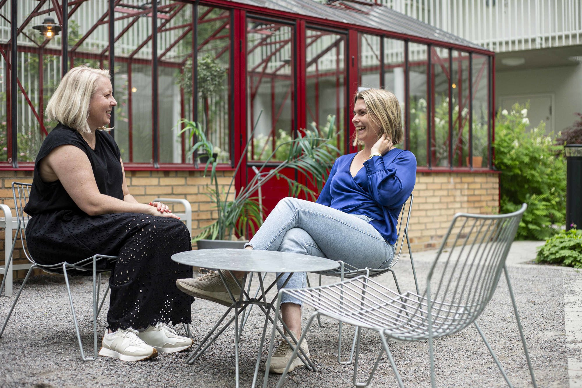 Två kvinnor sitter och skrattar och pratar på en av gårdarna i Vega